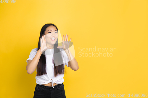 Image of Portrait of young asian woman isolated on yellow studio background