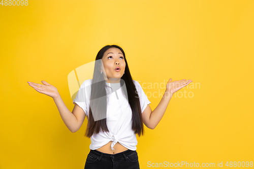 Image of Portrait of young asian woman isolated on yellow studio background