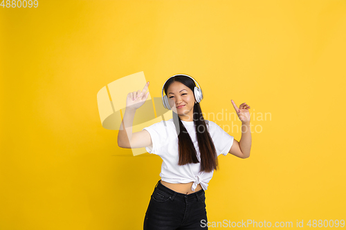 Image of Portrait of young asian woman isolated on yellow studio background