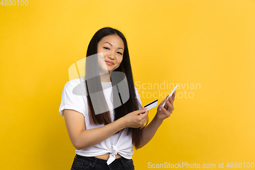 Image of Portrait of young asian woman isolated on yellow studio background