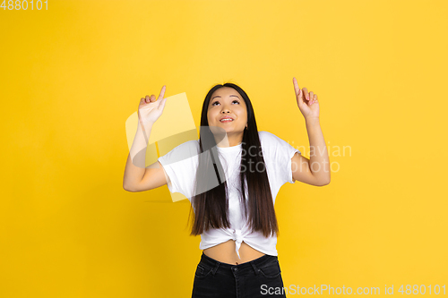 Image of Portrait of young asian woman isolated on yellow studio background