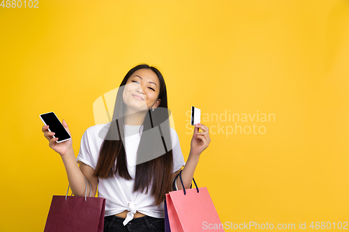 Image of Portrait of young asian woman isolated on yellow studio background