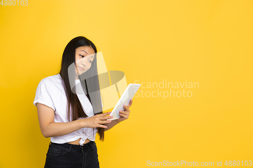 Image of Portrait of young asian woman isolated on yellow studio background