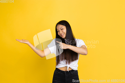 Image of Portrait of young asian woman isolated on yellow studio background