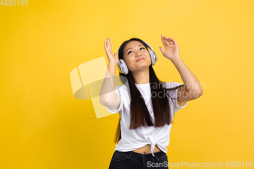 Image of Portrait of young asian woman isolated on yellow studio background