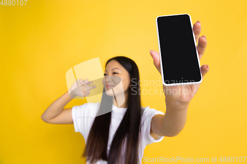 Image of Portrait of young asian woman isolated on yellow studio background