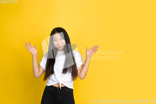 Image of Portrait of young asian woman isolated on yellow studio background