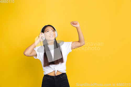 Image of Portrait of young asian woman isolated on yellow studio background