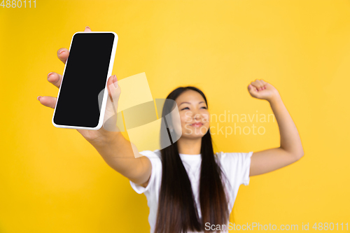 Image of Portrait of young asian woman isolated on yellow studio background