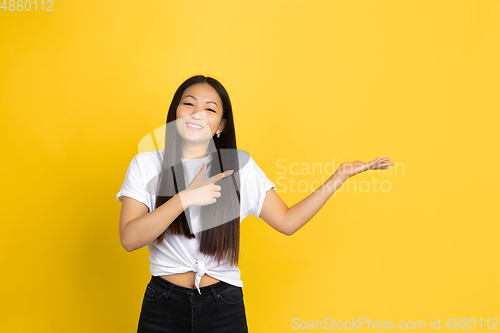 Image of Portrait of young asian woman isolated on yellow studio background