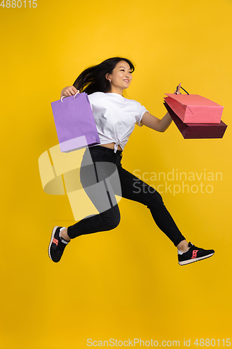 Image of Portrait of young asian woman isolated on yellow studio background