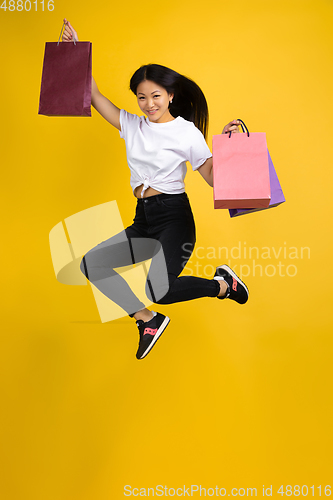 Image of Portrait of young asian woman isolated on yellow studio background