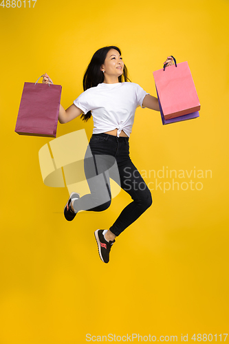 Image of Portrait of young asian woman isolated on yellow studio background