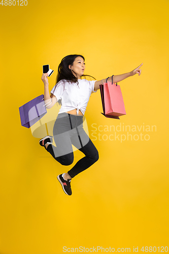 Image of Portrait of young asian woman isolated on yellow studio background