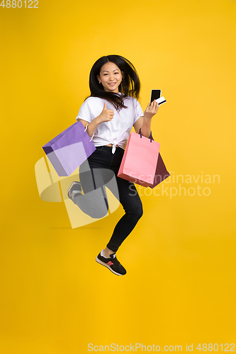 Image of Portrait of young asian woman isolated on yellow studio background