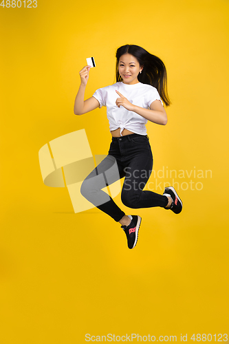 Image of Portrait of young asian woman isolated on yellow studio background