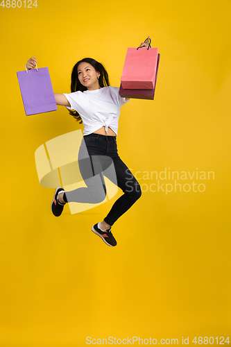 Image of Portrait of young asian woman isolated on yellow studio background