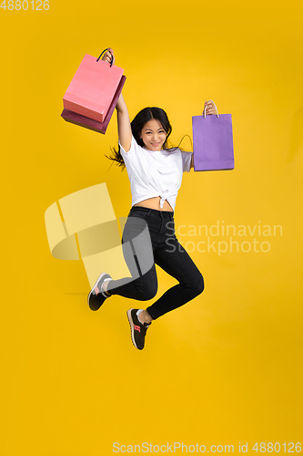 Image of Portrait of young asian woman isolated on yellow studio background