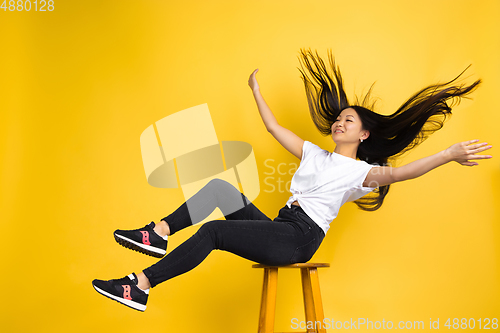 Image of Portrait of young asian woman isolated on yellow studio background