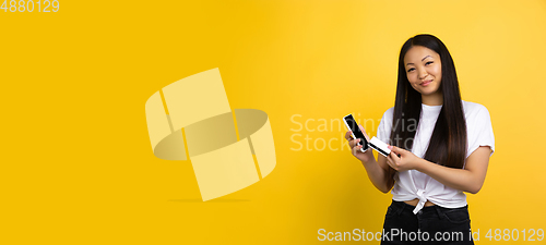 Image of Portrait of young asian woman isolated on yellow studio background