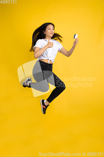 Image of Portrait of young asian woman isolated on yellow studio background