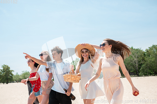 Image of Seasonal feast at beach resort. Group of friends celebrating, resting, having fun on the beach in sunny summer day