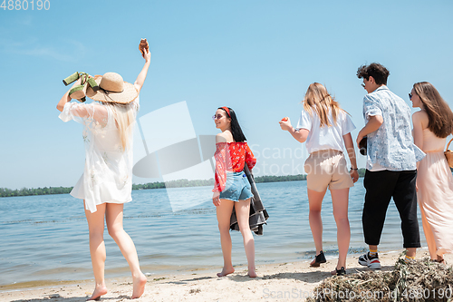 Image of Seasonal feast at beach resort. Group of friends celebrating, resting, having fun on the beach in sunny summer day