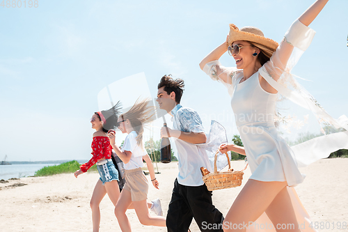 Image of Seasonal feast at beach resort. Group of friends celebrating, resting, having fun on the beach in sunny summer day