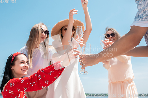 Image of Seasonal feast at beach resort. Group of friends celebrating, resting, having fun on the beach in sunny summer day