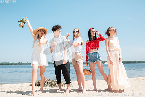 Image of Seasonal feast at beach resort. Group of friends celebrating, resting, having fun on the beach in sunny summer day