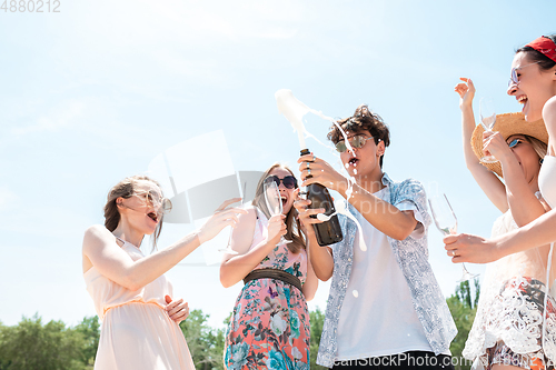 Image of Seasonal feast at beach resort. Group of friends celebrating, resting, having fun on the beach in sunny summer day