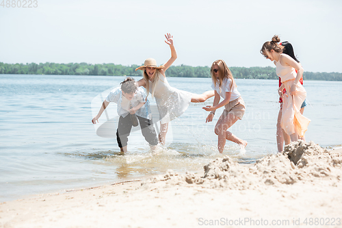 Image of Seasonal feast at beach resort. Group of friends celebrating, resting, having fun on the beach in sunny summer day