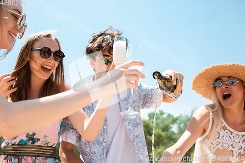 Image of Seasonal feast at beach resort. Group of friends celebrating, resting, having fun on the beach in sunny summer day