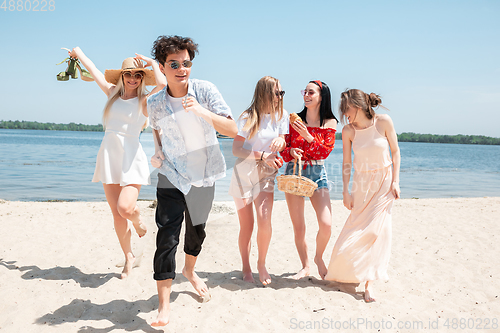 Image of Seasonal feast at beach resort. Group of friends celebrating, resting, having fun on the beach in sunny summer day