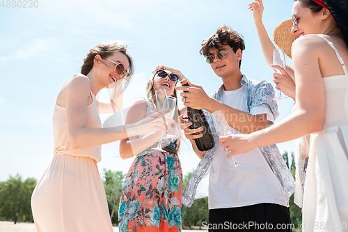 Image of Seasonal feast at beach resort. Group of friends celebrating, resting, having fun on the beach in sunny summer day