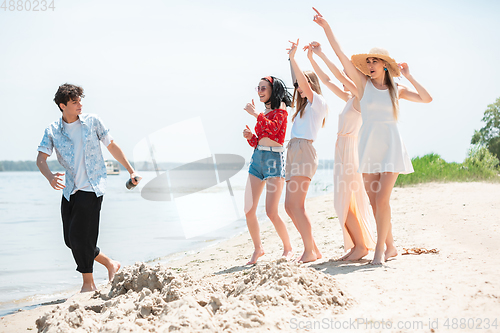 Image of Seasonal feast at beach resort. Group of friends celebrating, resting, having fun on the beach in sunny summer day