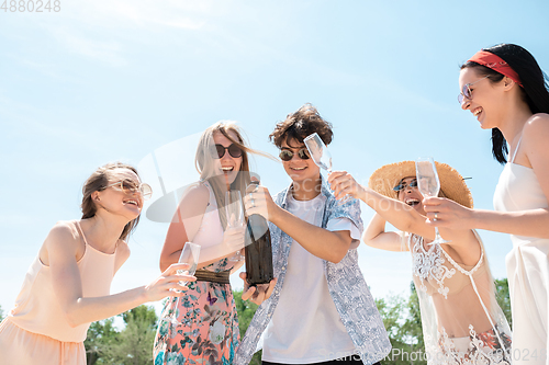 Image of Seasonal feast at beach resort. Group of friends celebrating, resting, having fun on the beach in sunny summer day