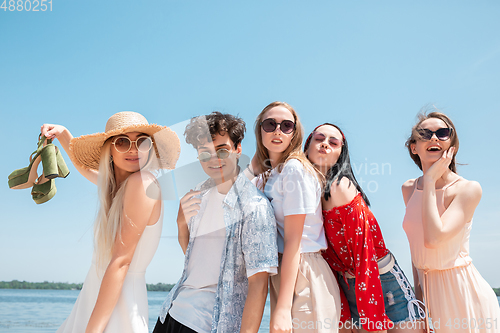 Image of Seasonal feast at beach resort. Group of friends celebrating, resting, having fun on the beach in sunny summer day