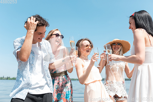 Image of Seasonal feast at beach resort. Group of friends celebrating, resting, having fun on the beach in sunny summer day