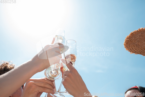 Image of Seasonal feast at beach resort. Group of friends celebrating, resting, having fun on the beach in sunny summer day