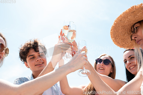 Image of Seasonal feast at beach resort. Group of friends celebrating, resting, having fun on the beach in sunny summer day