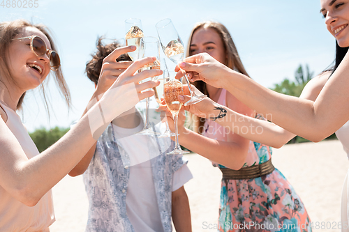 Image of Seasonal feast at beach resort. Group of friends celebrating, resting, having fun on the beach in sunny summer day