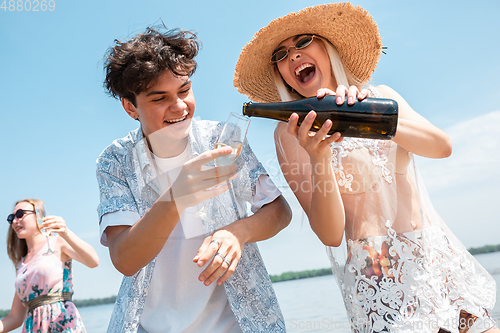 Image of Seasonal feast at beach resort. Group of friends celebrating, resting, having fun on the beach in sunny summer day