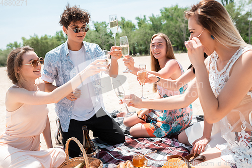 Image of Seasonal feast at beach resort. Group of friends celebrating, resting, having fun on the beach in sunny summer day