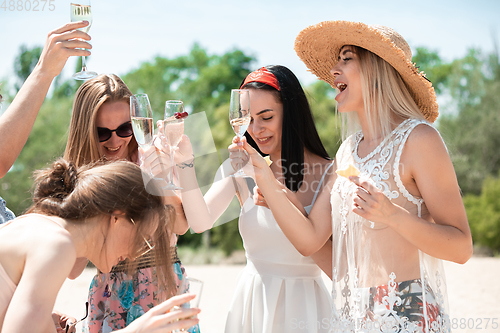 Image of Seasonal feast at beach resort. Group of friends celebrating, resting, having fun on the beach in sunny summer day