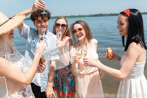 Image of Seasonal feast at beach resort. Group of friends celebrating, resting, having fun on the beach in sunny summer day