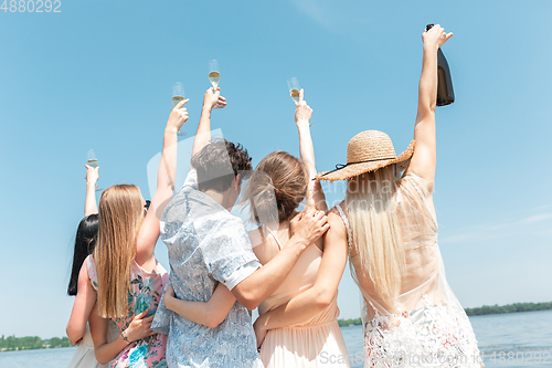 Image of Seasonal feast at beach resort. Group of friends celebrating, resting, having fun on the beach in sunny summer day