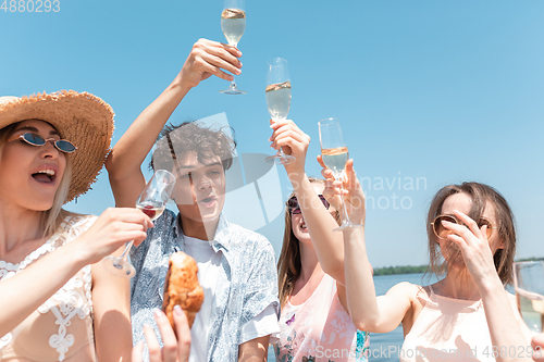 Image of Seasonal feast at beach resort. Group of friends celebrating, resting, having fun on the beach in sunny summer day