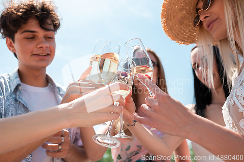 Image of Seasonal feast at beach resort. Group of friends celebrating, resting, having fun on the beach in sunny summer day