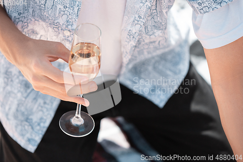 Image of Seasonal feast at beach resort. Close up hands of man celebrating, resting, having fun, clinking glasses on sky background